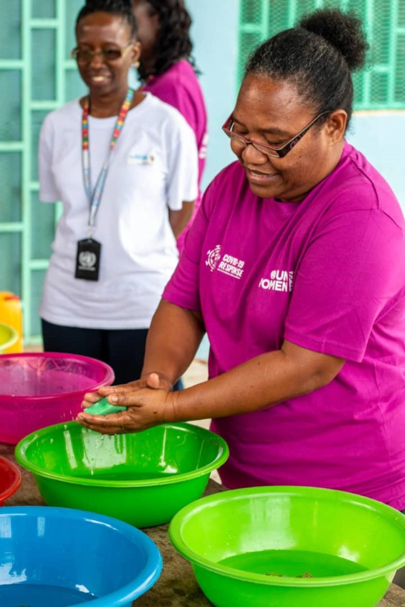 A woman washes hands with soap and water in workshop.