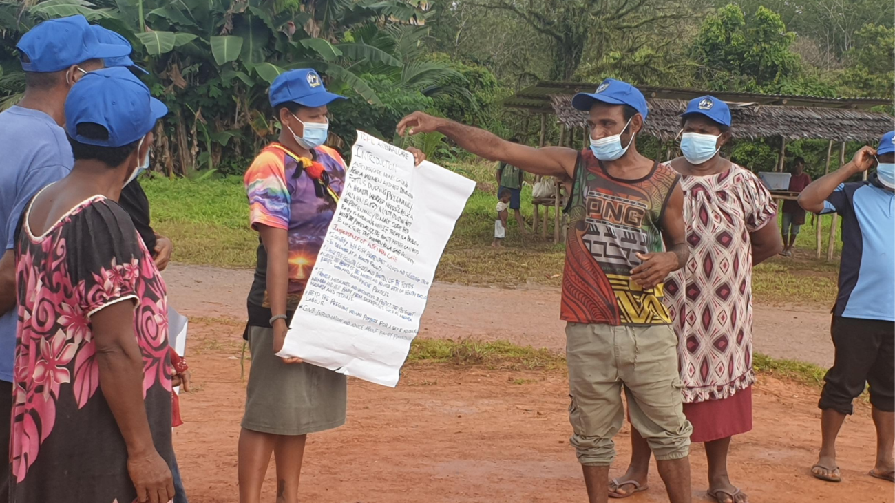 Man stands with poster explaining health and hygiene messages.