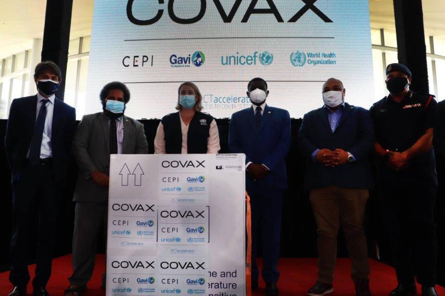 UN team members and government representatives stand with COVAX box.