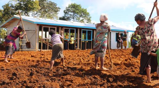 Women digging in field to prepare for building construction. 