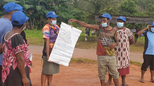 Man stands with poster explaining health and hygiene messages.